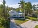 Aerial view of a charming home with gravel driveway, lush landscaping, and mature palm trees at 206 23Rd W St, Bradenton, FL 34205