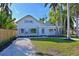 Charming exterior shows blue accents, palm trees, green grass and a white rock driveway at 206 23Rd W St, Bradenton, FL 34205
