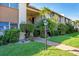 Well-maintained condo complex with lush landscaping, including palm trees and manicured shrubs, under a bright blue sky at 2446 Clubhouse Cir # 202, Sarasota, FL 34232