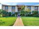 Inviting condo exterior with lush landscaping, sidewalk, and second-story balcony, showcasing a well-maintained community at 2446 Clubhouse Cir # 202, Sarasota, FL 34232