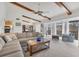 Spacious living room with beamed ceilings, a fan, and a sliding glass door leading to a balcony at 2446 Clubhouse Cir # 202, Sarasota, FL 34232