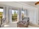 Sitting area with large windows with pleasant views, white curtains, and a comfortable armchair and ottoman at 2446 Clubhouse Cir # 202, Sarasota, FL 34232