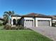 Charming home with a tile roof, three-car garage, palm trees, and meticulous landscaping at 26800 Pavin Dr, Englewood, FL 34223