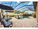 Screened-in pool area featuring a geometrically shaped pool and multiple seating areas at 26800 Pavin Dr, Englewood, FL 34223