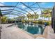 A screened-in pool with clear blue water and a spacious tiled deck, surrounded by lush greenery at 26800 Pavin Dr, Englewood, FL 34223