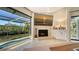 Bright living room featuring a cozy fireplace, a large flat screen, and expansive views of a screened-in pool and waterway at 3151 Bayou Sound, Longboat Key, FL 34228