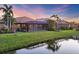 Backyard view of homes with screened lanais, lush green lawns, and a serene pond at 3715 80Th E Dr, Sarasota, FL 34243