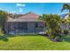 An attractive backyard with a screened pool and well-maintained landscaping with decorative plants and green lawn at 3715 80Th E Dr, Sarasota, FL 34243