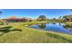 A serene backyard view featuring a screened lanai, lush green lawn, and a tranquil pond reflecting the clear blue sky at 3715 80Th E Dr, Sarasota, FL 34243