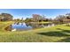 Scenic view of a calm pond reflecting trees and sky, surrounded by manicured green grass and a natural landscape at 3715 80Th E Dr, Sarasota, FL 34243