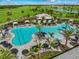 Aerial view of a resort-style pool with ample lounge chairs, umbrellas, palm trees, and a poolside bar overlooking a golf course at 4717 Zeno Ct, Bradenton, FL 34211