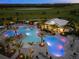 Aerial view of the large pool area with palm trees, lounge chairs, and umbrellas against the backdrop of a golf course at night at 4717 Zeno Ct, Bradenton, FL 34211