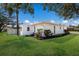 View of the backyard and side of the home with green grass, landscaping and white exterior walls at 5011 Live Oak Cir # 65, Bradenton, FL 34207