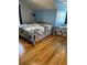 Bedroom featuring wood floors, a large bed with decorative ocean themed comforter, and a dark window curtain at 503 1St Nw Ave, Ruskin, FL 33570