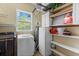 Well-organized laundry room with storage shelves, white appliances, and a window providing natural light at 503 1St Nw Ave, Ruskin, FL 33570