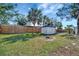 A wooden fence encloses a grassy backyard featuring a storage shed, green trees, and lush green grass at 5061 Placida Rd # A, Englewood, FL 34224