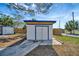 Outdoor storage shed with double doors and concrete pad in fenced backyard under a blue sky with mature trees at 5061 Placida Rd # A, Englewood, FL 34224