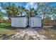 Two white storage sheds with blue trim are positioned in a grassy yard and enclosed by a wooden fence at 5061 Placida Rd # A, Englewood, FL 34224