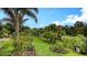 Lush backyard featuring vibrant landscaping, tropical trees, and an expansive green lawn at 5068 Inshore Landing Dr, Apollo Beach, FL 33572