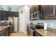 This kitchen is equipped with stainless steel appliances, granite countertops, and dark wood cabinets at 5068 Inshore Landing Dr, Apollo Beach, FL 33572
