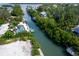 Scenic aerial view of a waterfront property with a boat dock and lush tropical landscaping along the canal at 552 Juan Anasco Drive, Longboat Key, FL 34228