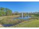 Picturesque view of a lush pond with a fountain in front of the complex on a clear, sunny day at 5601 Bentgrass Dr # 10-115, Sarasota, FL 34235