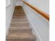 Carpeted staircase with a wooden handrail leading to the upper level of the home at 5734 Archipelago St, Nokomis, FL 34275