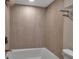 Bathroom with a white tub and shower, light wood paneled walls and a chrome shower and towel rack at 5757 Gulf Of Mexico Dr # 110, Longboat Key, FL 34228