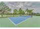 Well-maintained community tennis court with vibrant blue surface and surrounding green landscaping at 7623 Camminare Dr, Sarasota, FL 34238