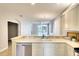 Bright kitchen featuring white cabinetry, tile backsplash, and a breakfast bar overlooking the living area at 8536 54Th Avenue E Cir, Bradenton, FL 34211