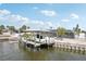 Canal-front home with a boat dock featuring a covered boat lift, boat, and lush landscaping at 928 Spindle Palm Way, Apollo Beach, FL 33572