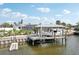 Canal-front home with a boat dock featuring a covered boat lift, boat and lush landscaping at 928 Spindle Palm Way, Apollo Beach, FL 33572