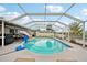 The screened-in swimming pool area has outdoor furniture, a mounted television, and waterfront canal access at 928 Spindle Palm Way, Apollo Beach, FL 33572