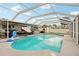 Screened-in swimming pool with shallow end, set up with outdoor furniture, mounted television, and canal access at 928 Spindle Palm Way, Apollo Beach, FL 33572