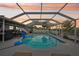 Sunset view of a private screened-in pool with clear blue water surrounded by a spacious deck at 928 Spindle Palm Way, Apollo Beach, FL 33572