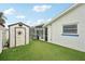 Backyard featuring a storage shed complemented by a green artificial turf lawn, enhancing outdoor aesthetics at 928 Spindle Palm Way, Apollo Beach, FL 33572