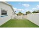 Side yard showcasing well-maintained artificial turf and a charming white picket fence for a clean aesthetic at 928 Spindle Palm Way, Apollo Beach, FL 33572