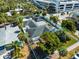 An aerial view of a fenced single-Gathering home with a dark roof surrounded by many palm trees on a sunny day at 106 N Blvd Of The Presidents, Sarasota, FL 34236