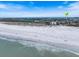 Scenic view of a sandy beach with gentle waves, scattered beachgoers enjoying the sunny day, and picturesque waterfront homes at 106 N Blvd Of The Presidents, Sarasota, FL 34236