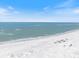 Tranquil beachfront scene with clear skies over a sandy beach with gentle waves and a few distant figures at 106 N Blvd Of The Presidents, Sarasota, FL 34236