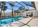 Beautiful pool area featuring a screened-in enclosure, travertine patio and lush tropical landscaping at 106 N Blvd Of The Presidents, Sarasota, FL 34236