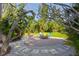Cozy backyard firepit area features brickwork, stone details, and comfortable seating, surrounded by lush greenery at 109 Burney Rd, Osprey, FL 34229