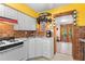 Kitchen with white appliances and cabinets, yellow walls, and wood-trimmed doorway to adjacent room at 109 Burney Rd, Osprey, FL 34229