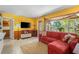 Comfortable living room features a large window with view of backyard, a red sectional couch, and colorful decor at 109 Burney Rd, Osprey, FL 34229