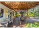 Inviting outdoor patio with wooden pergola offers a dining area and comfortable seating, ideal for entertaining at 109 Burney Rd, Osprey, FL 34229