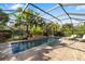 Screened-in pool area with a waterfall feature, tropical landscaping, brick paver deck, and lounge chairs at 1106 Brambling Ct, Bradenton, FL 34212