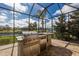 Outdoor kitchen with stainless steel grill, stone countertops, and a beverage fridge offers a luxurious outdoor cooking experience at 11739 River Shores Trl, Parrish, FL 34219