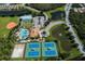 An aerial view showcases sports and pool amenities including tennis and basketball courts and winding roadways in a neighborhood at 12022 Granite Woods Loop, Venice, FL 34292