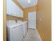 Laundry room with modern washer and dryer units, white cabinets, and neutral tile flooring at 12022 Granite Woods Loop, Venice, FL 34292