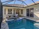 Screened-in pool with a spa and outdoor seating with a table at 12022 Granite Woods Loop, Venice, FL 34292